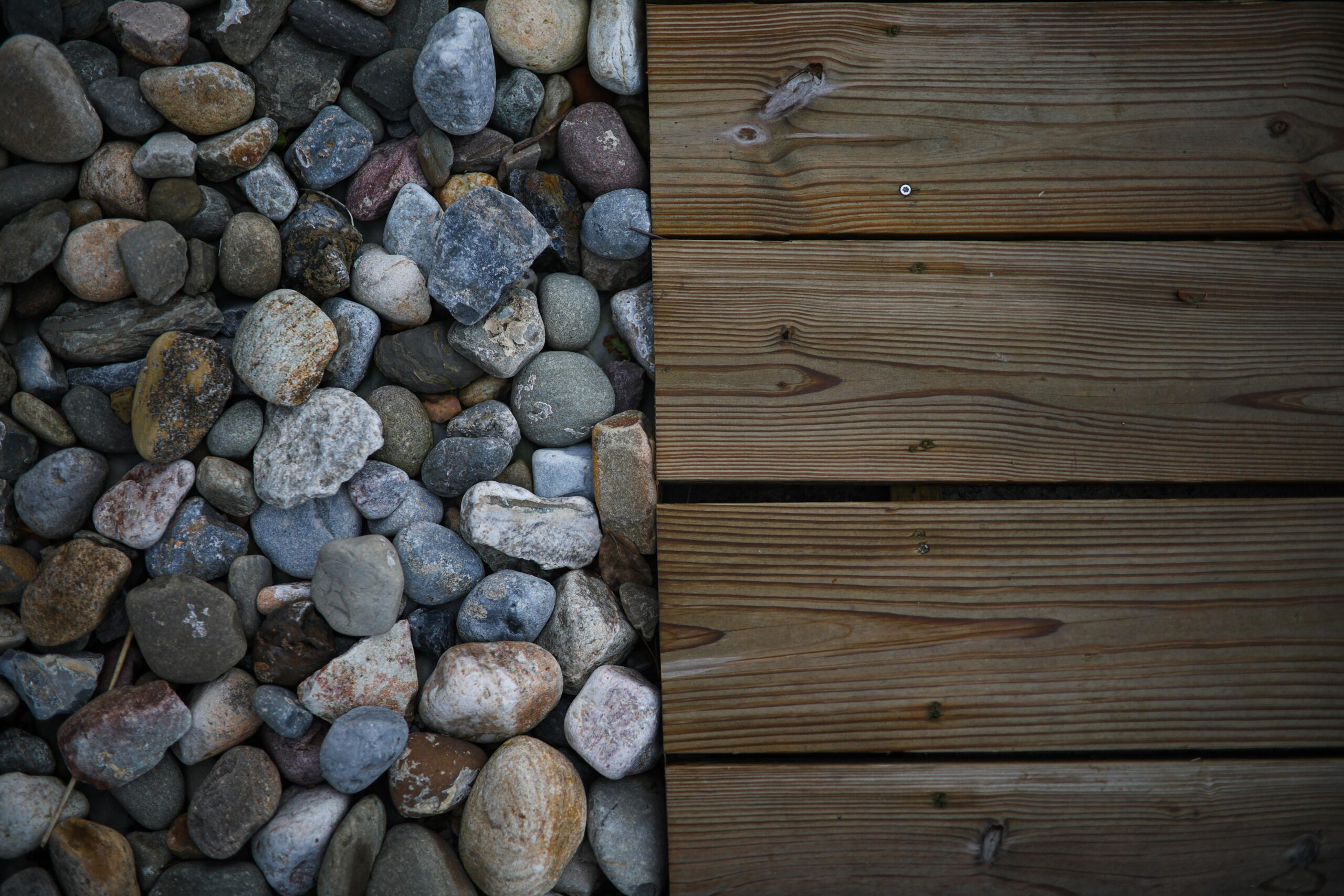 Aerial view of assorted stones next to wooden deck planks, showcasing textures.